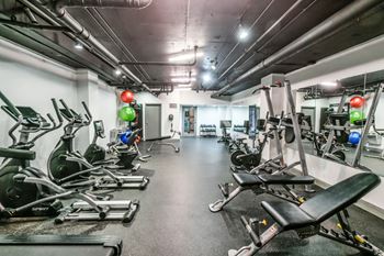 A gym with a row of treadmills and elliptical machines.
